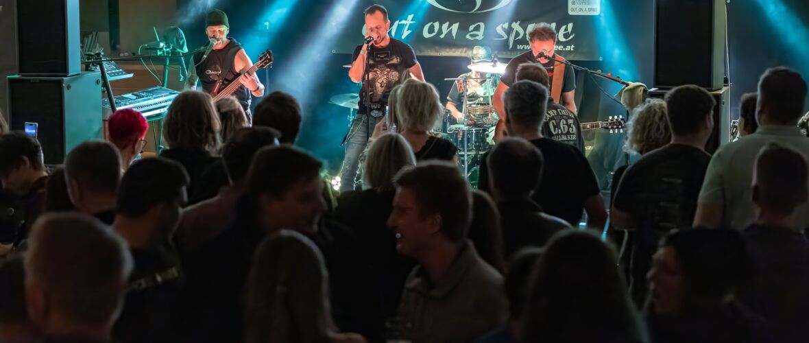Band spielt live in einem Club vor Publikum, Musiker mit Instrumenten auf der Bühne