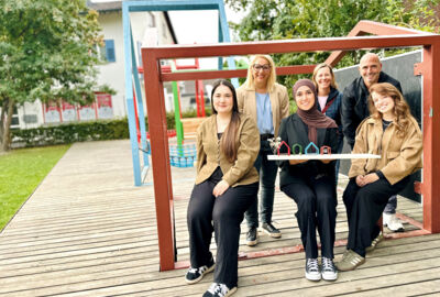 Sechs Personen halten ein Modell mit Häusern in einer Anlage in Österreich