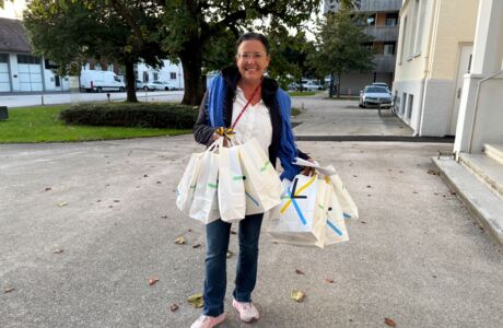 Frau mit Einkaufstaschen in der Hand steht vor einem Gebäude