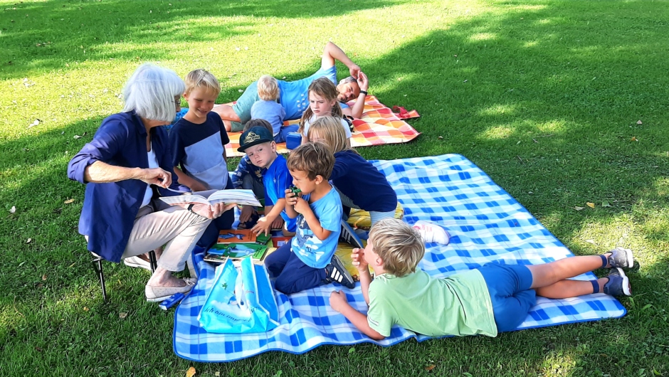 Gespannte ZuhörerInnen bei der Vorlesestunde am Spielplatz Wiesenrain mit Lesepatin Roswith Bösch (1)