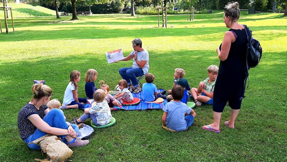 Gespannte ZuhöreInnen bei der Vorlesestunde am Spielplatz Wiesenrain mit Lesepatin Brigitte Muxel
