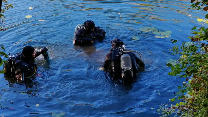 Taucher in Neoprenanzügen und mit Sauerstoffflaschen im Wasser bei einer Bergung